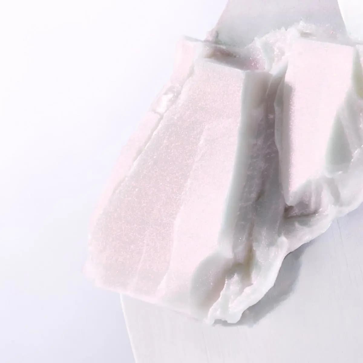 Close-up of shimmering pearly white balm texture smeared on a spatula