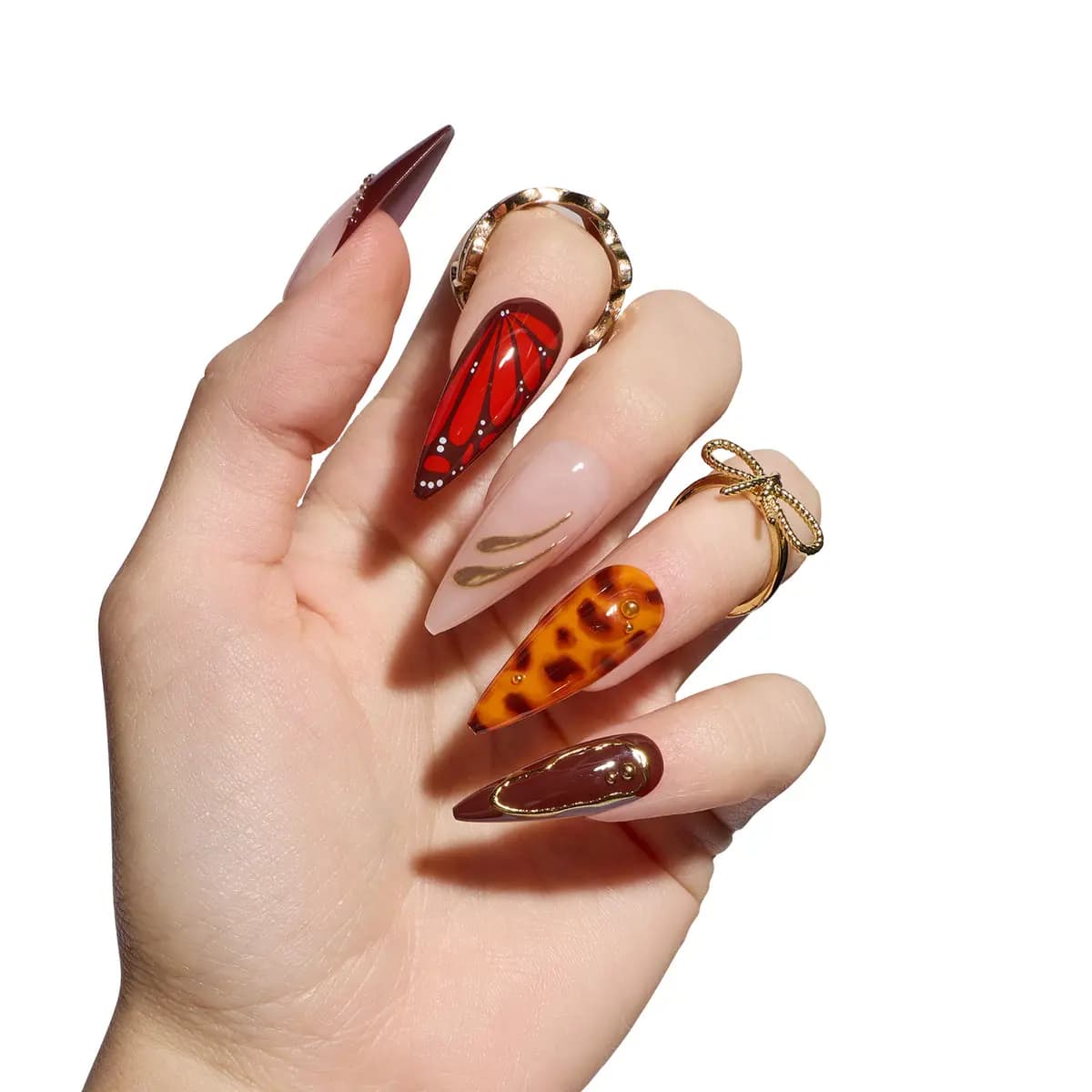 Hand wearing long stiletto Tortoiseshells nails: red butterfly wing, amber tortoise, nude with gold swirls, brown gold.