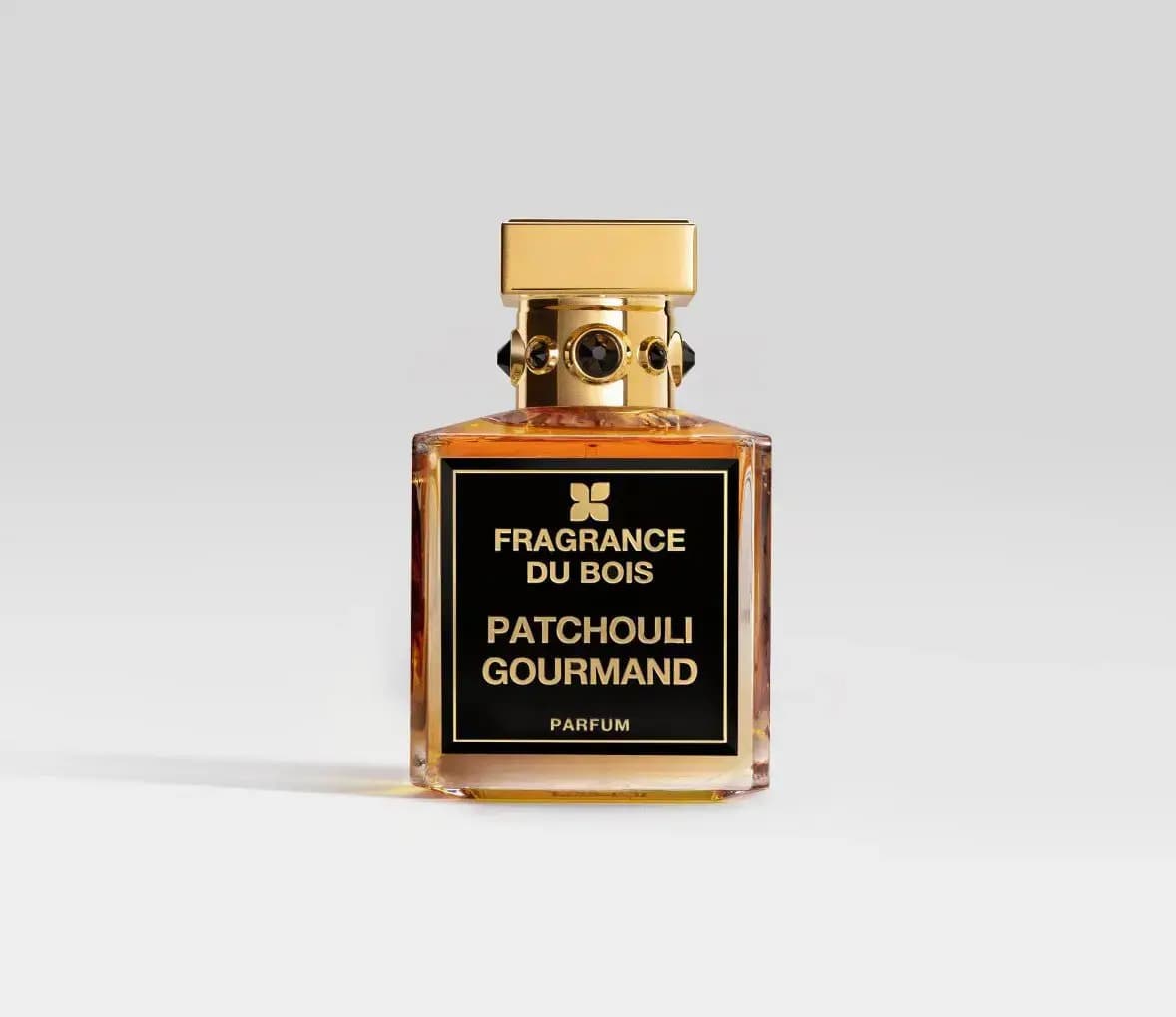 Fragrance Du Bois Patchouli Gourmand Parfum in amber glass with jewelled gold cap on plain grey background
