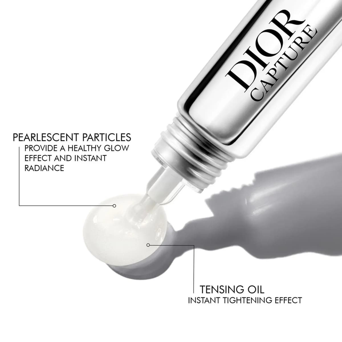 Close-up of the applicator tip dispensing a clear droplet, labeled with pearlescent particles and tensing oil callouts