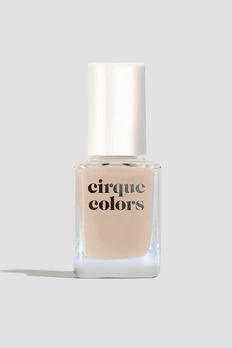 Single bottle of sheer peachy nude polish with a white cap on a light grey background