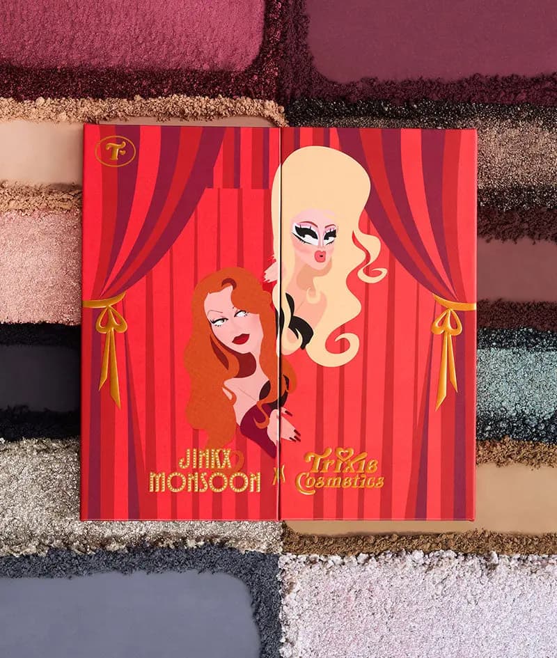 Closed Jinkx Monsoon x Trixie Cosmetics palette with cartoon portraits between red curtains on crushed shadow swatches