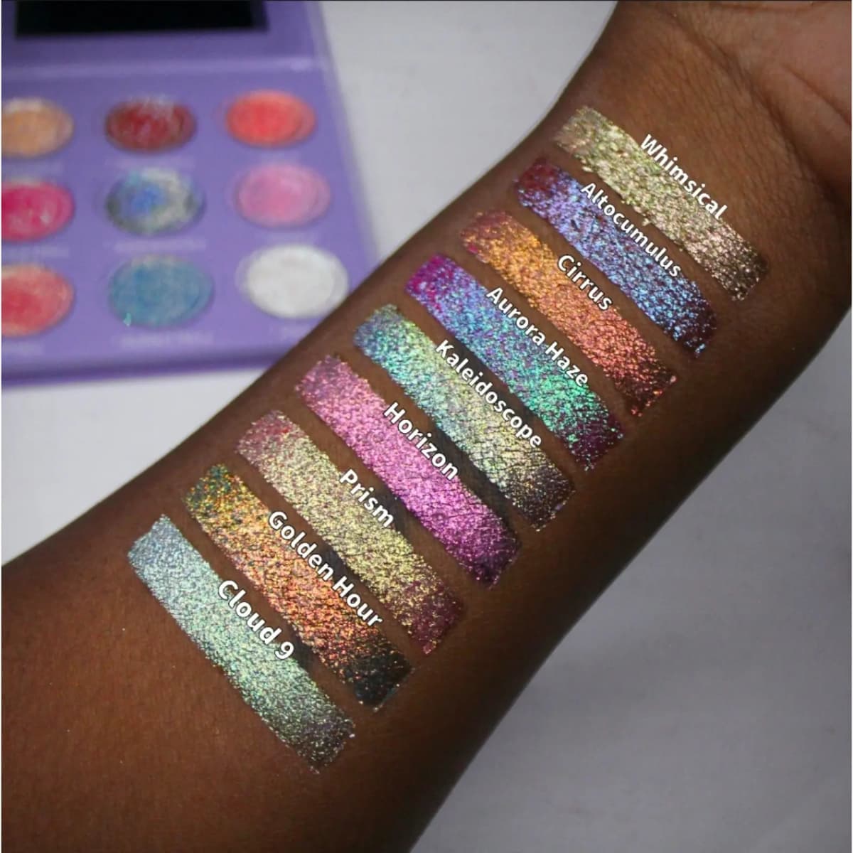 Labelled multichrome swatches on deep skin, from Whimsical and Altocumulus to Prism, Golden Hour and Cloud 9