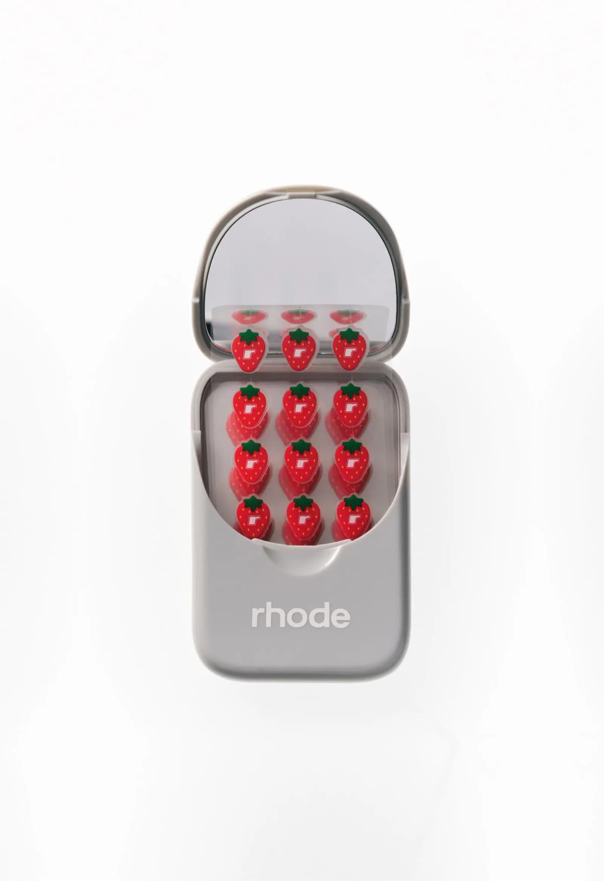 Open grey case with mirror inside the lid, holding red strawberry-shaped Spotwear stickers with an r logo