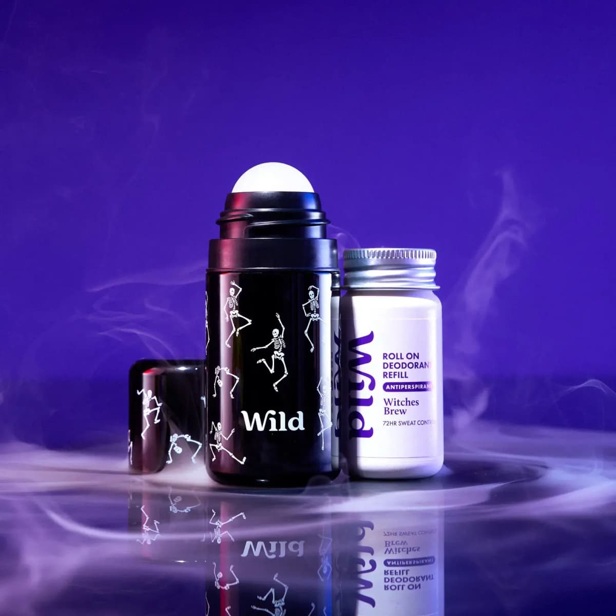 Wild Dancing Skeletons roll-on case next to a white Witches Brew roll-on antiperspirant refill on a misty reflective surface