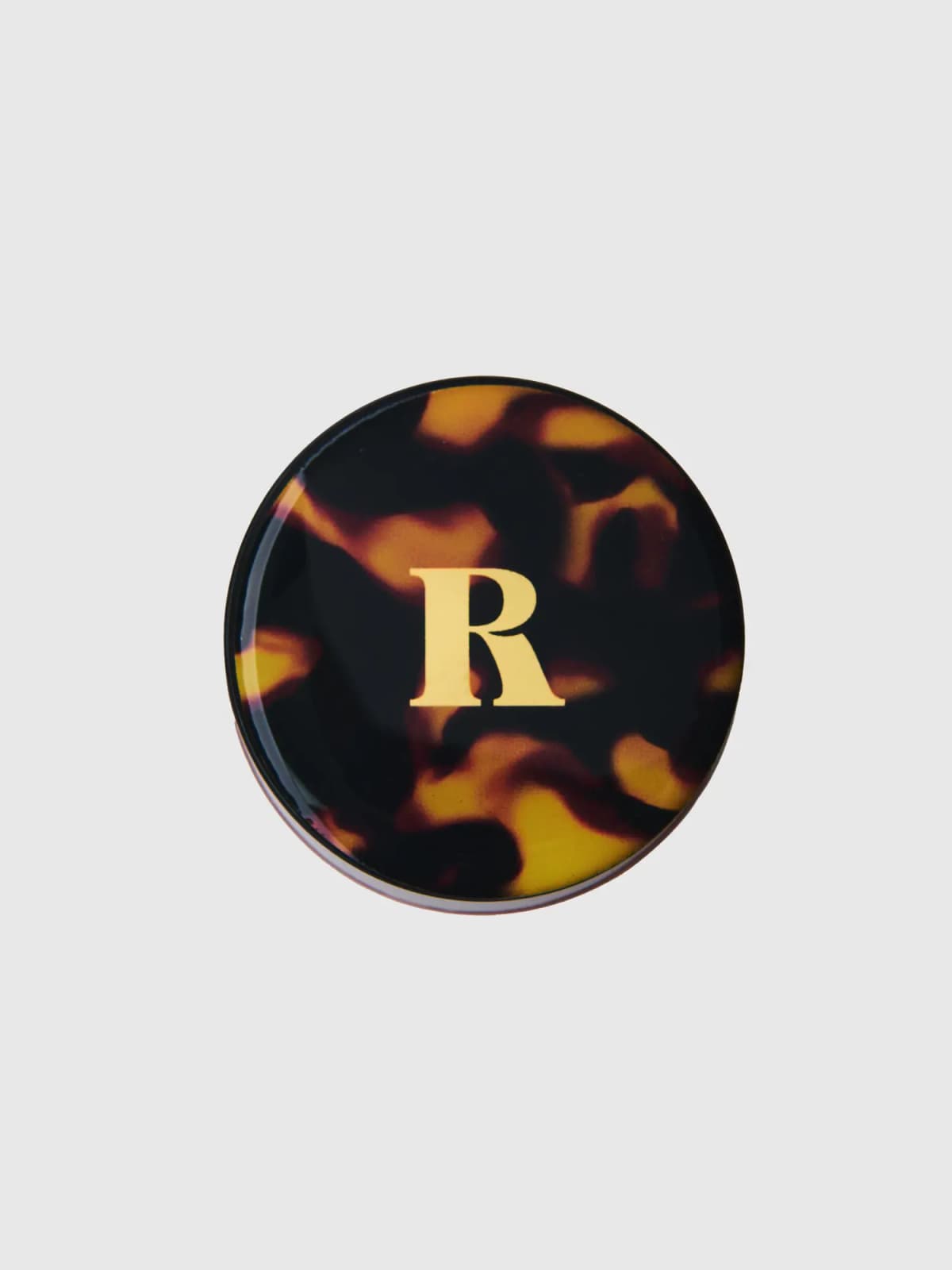 Tortoiseshell blush lid with a gold serif R monogram, viewed from above