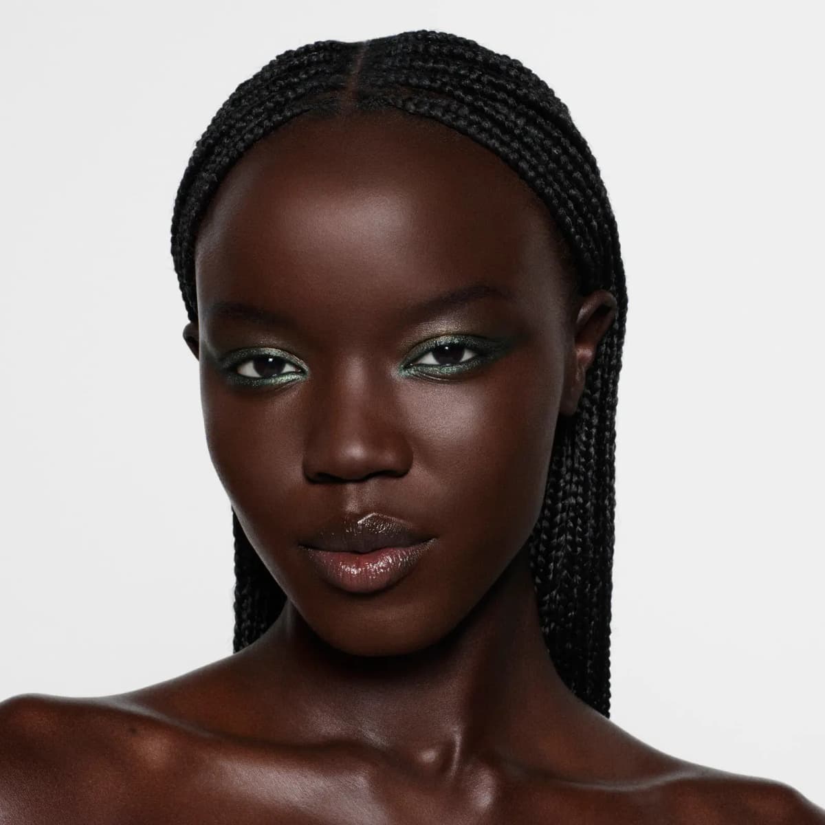 Model with braided hair wearing shimmering green and bronze eyeshadow with a winged olive liner