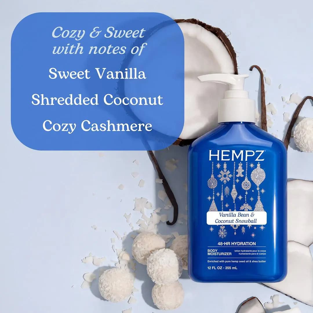 Blue Vanilla Bean & Coconut Snowball bottle laid flat with coconut halves, vanilla pods, and coconut snowball treats