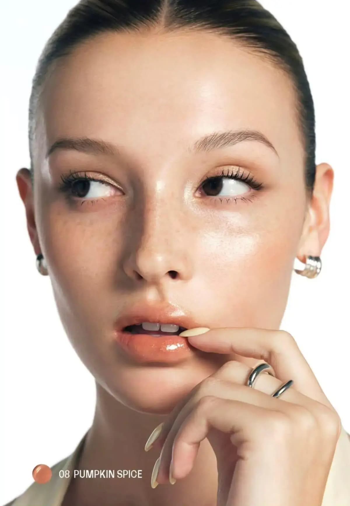 Model with slicked-back hair wearing glossy peach-orange lips, labelled 08 Pumpkin Spice