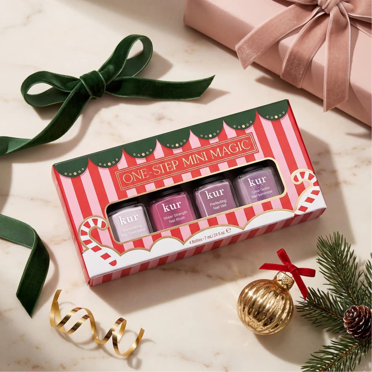 One-Step Mini Magic box on marble with a green velvet bow, pink gift, gold ornament and pine