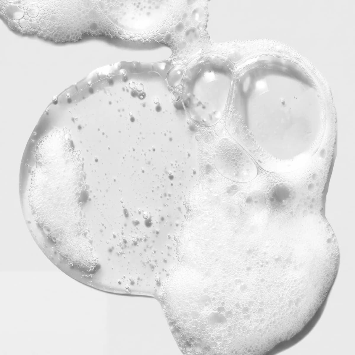 Close-up of clear cleanser gel turning into white foam with large and small bubbles