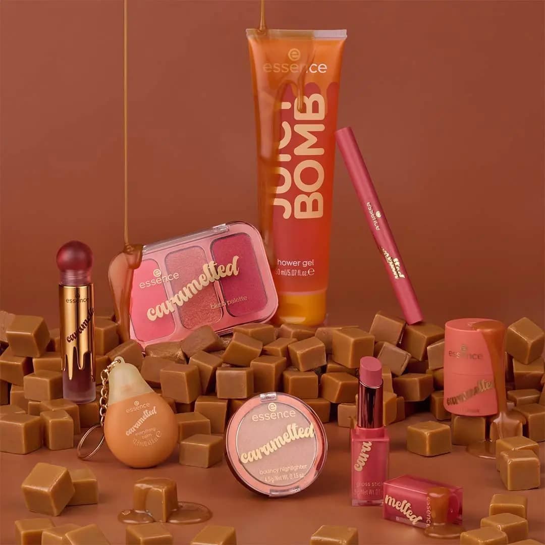 essence caramelted Trend Edition collection with shower gel, blush palette, lip products and highlighter among caramel cubes on a brown background