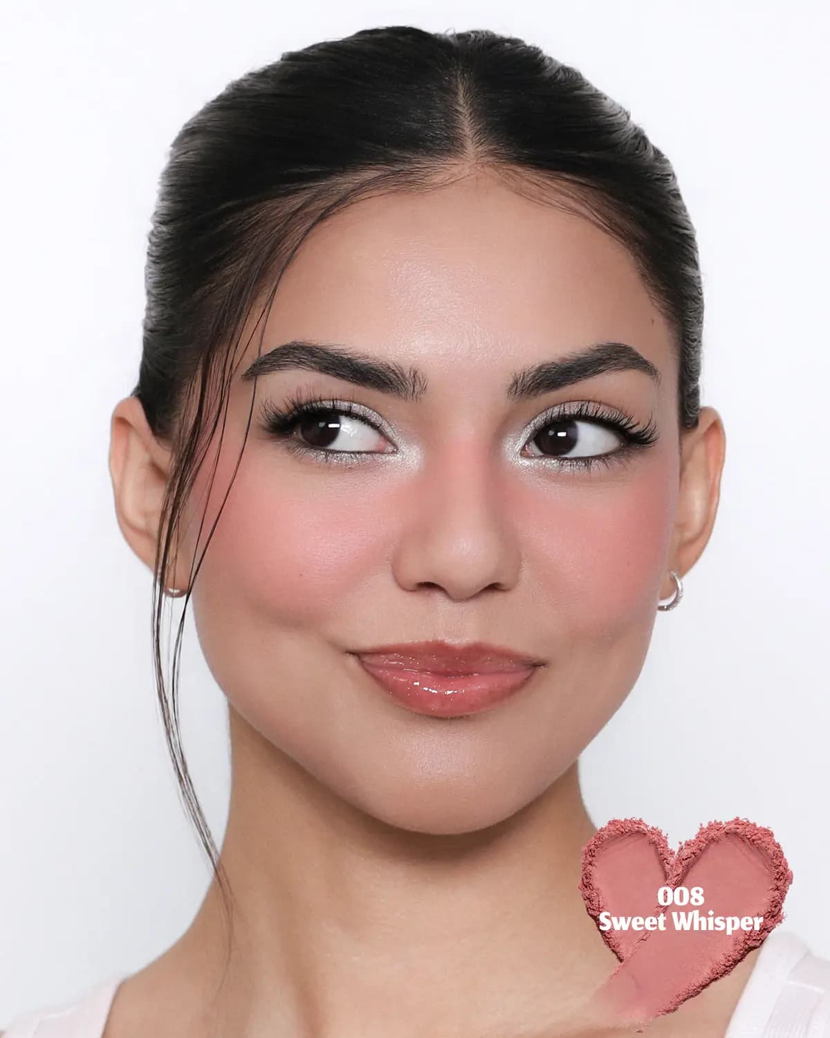 Model with slicked-back hair wearing a soft rosy blush, with a heart-shaped 008 Sweet Whisper powder swatch in the corner.