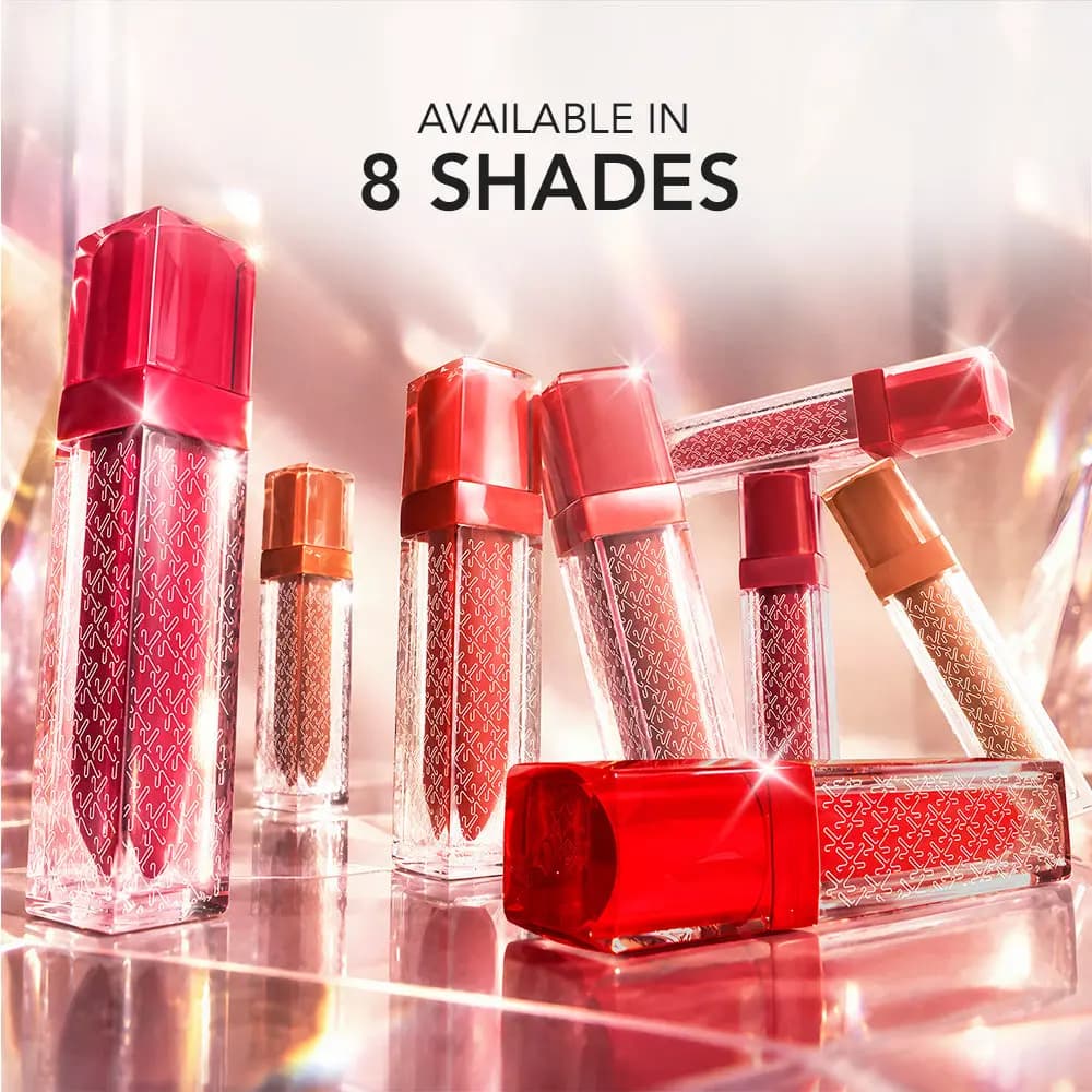 Kay Beauty lip gloss stain tubes in red and nude shades on a sparkly pink surface, captioned "Available in 8 shades