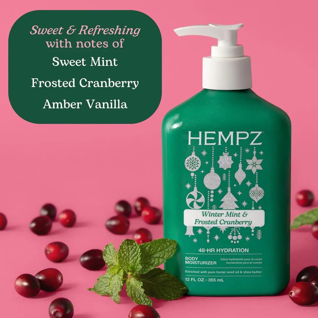 Green Winter Mint & Frosted Cranberry bottle on pink background surrounded by fresh cranberries and mint leaves