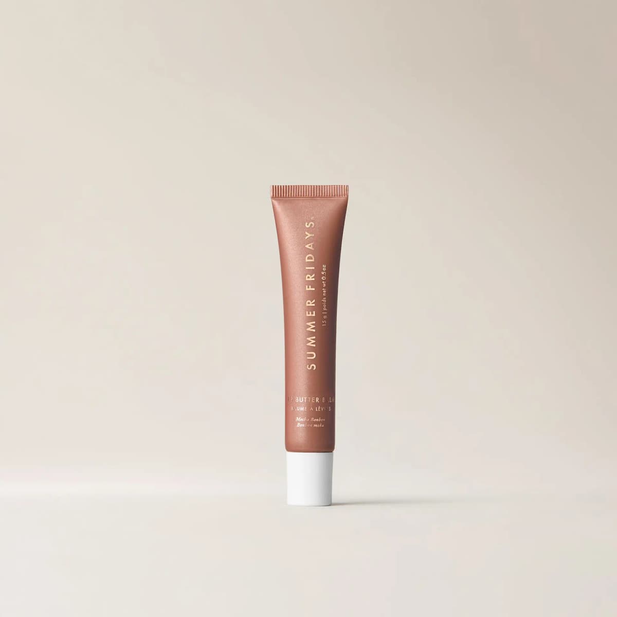 Shimmery bronze Mocha Bonbon Lip Butter Balm tube with white cap standing on a plain cream background