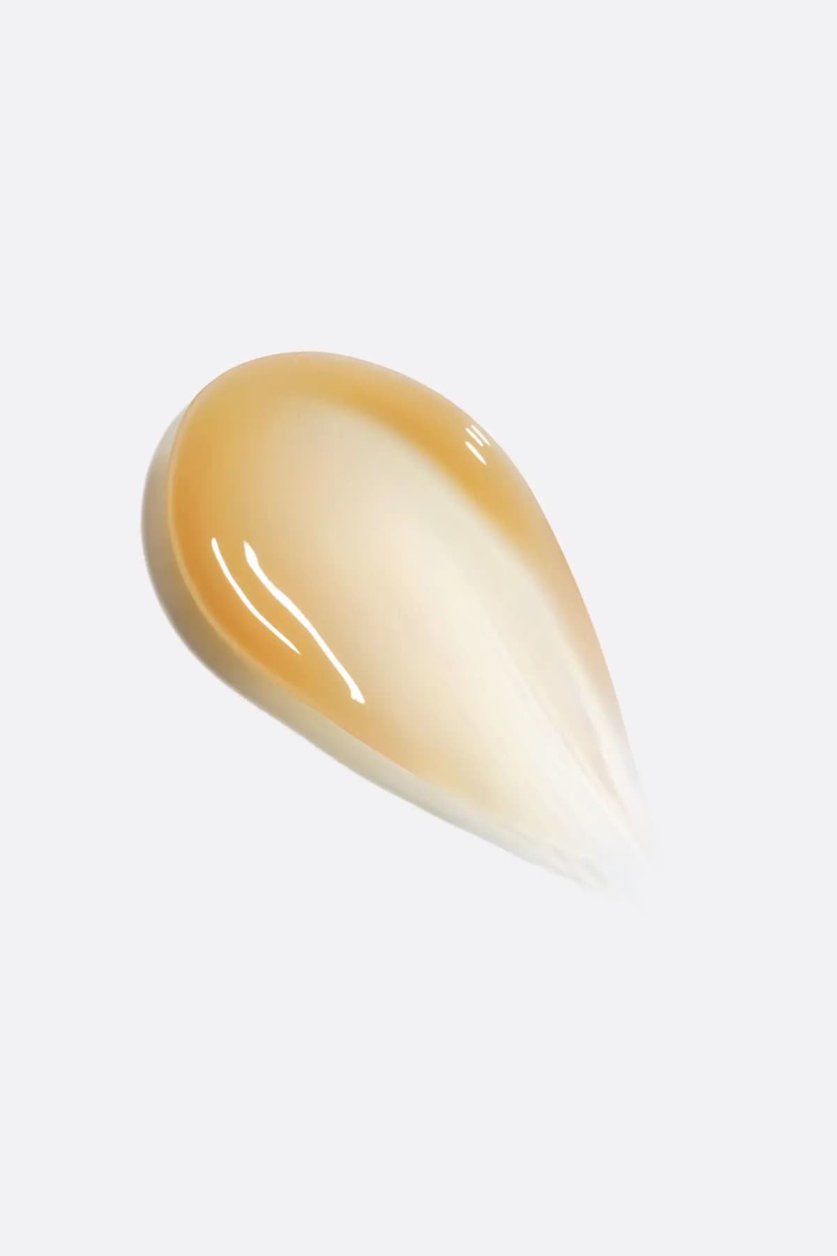 Glossy translucent amber-to-cream serum swatch smeared on a light grey background