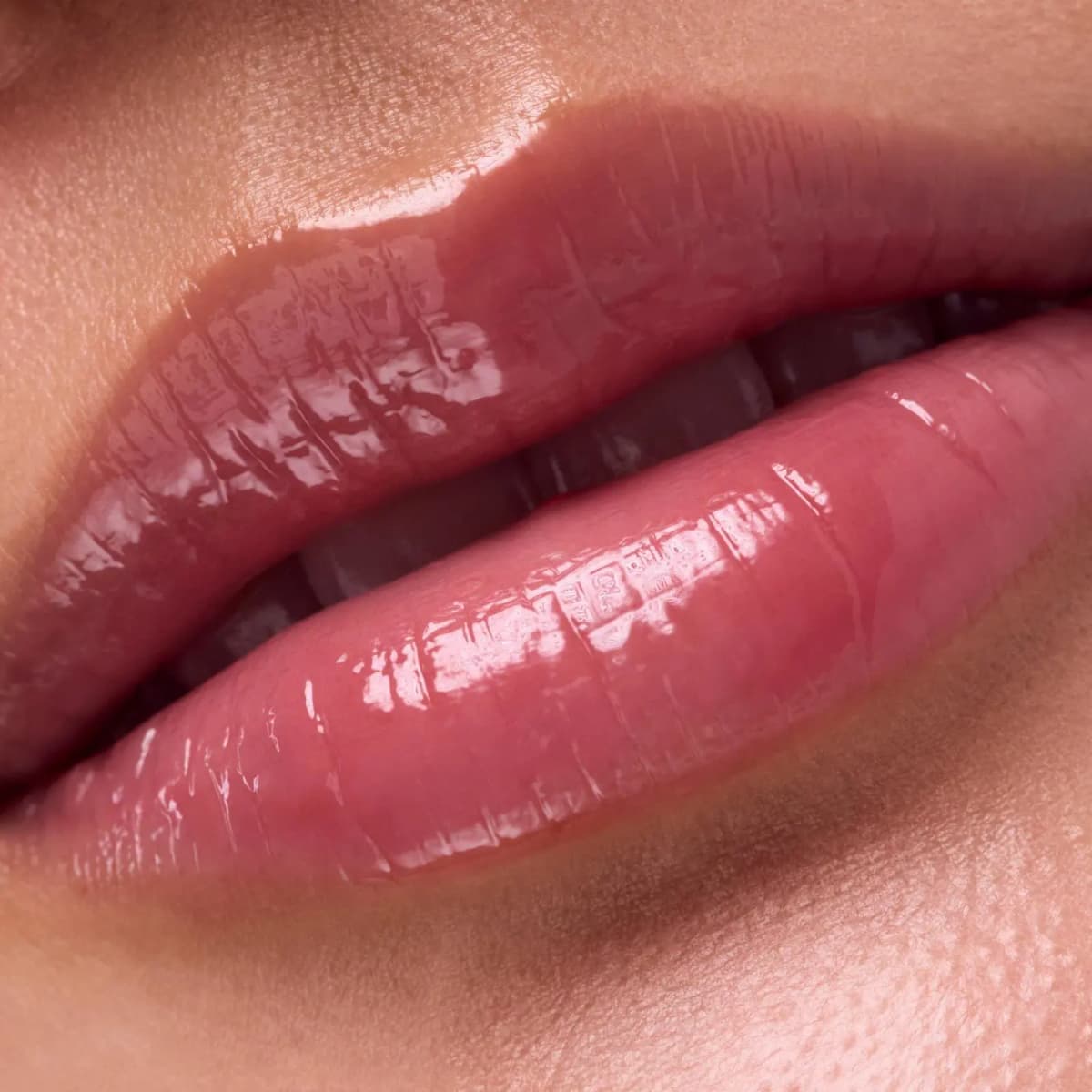 Close-up of lips with a sheer, glossy rosy-pink finish on fair skin