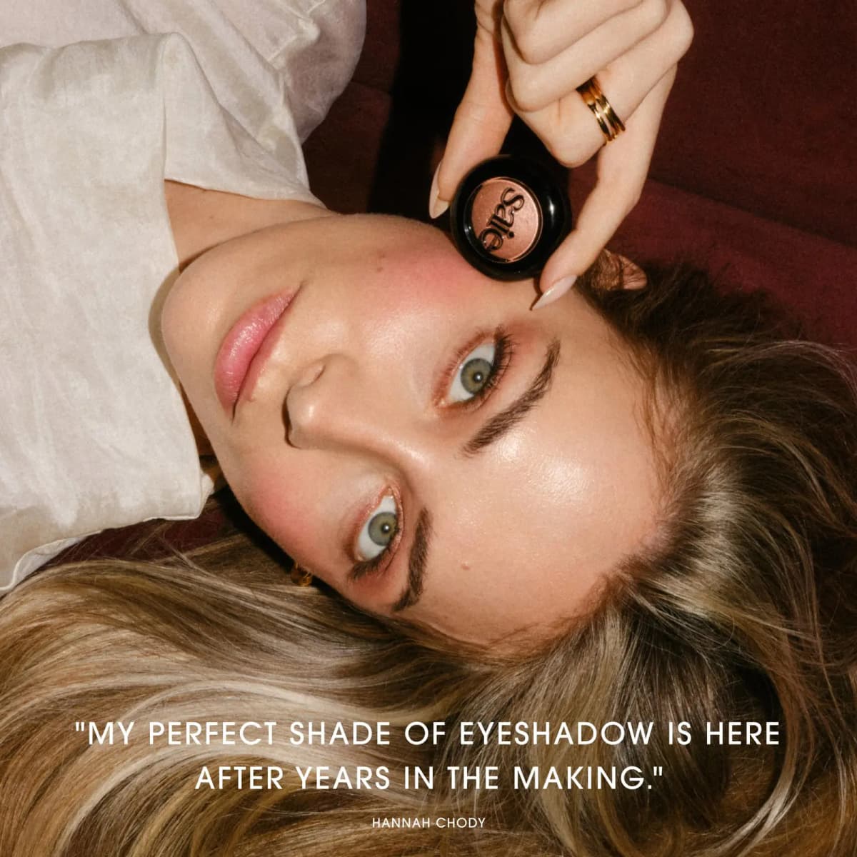 Hannah Chody lies on a red velvet sofa holding the compact, quote: "My perfect shade of eyeshadow is here …"