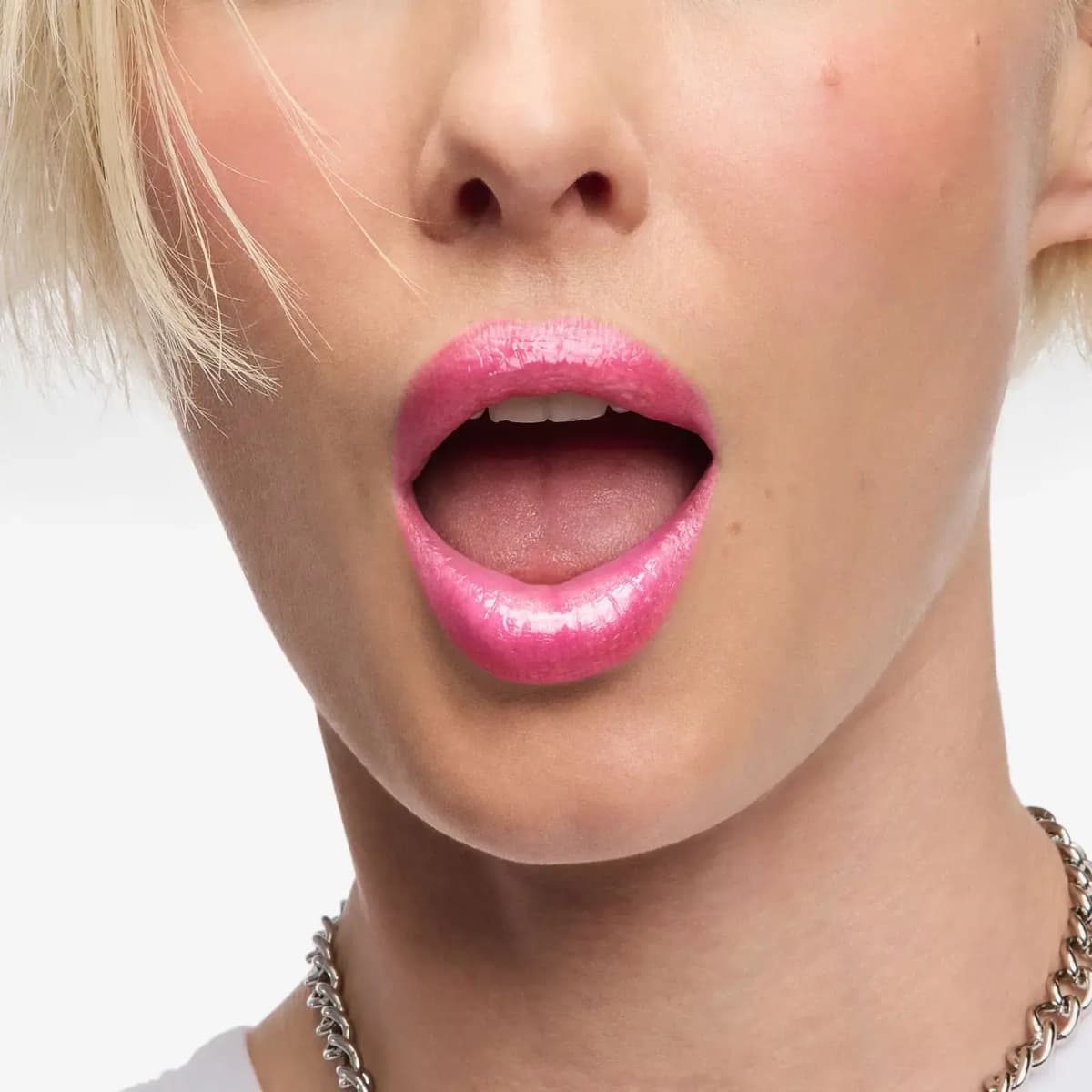 Close crop of an open mouth with sheer, shiny pink gloss, blonde hair strands and a chunky silver chain