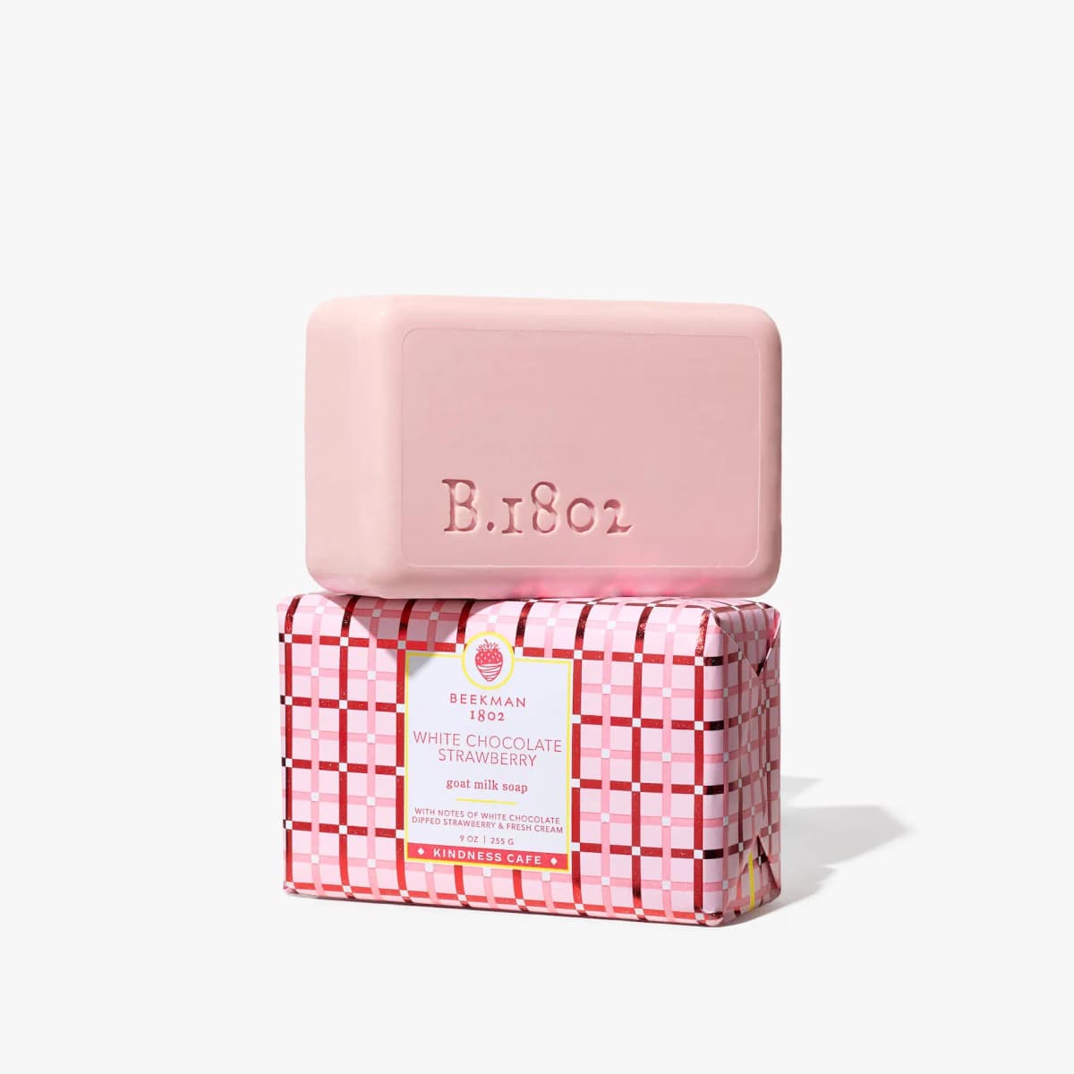 Pink Beekman 1802 White Chocolate Strawberry goat milk soap bar stamped B.1802, stacked on its plaid wrapped box