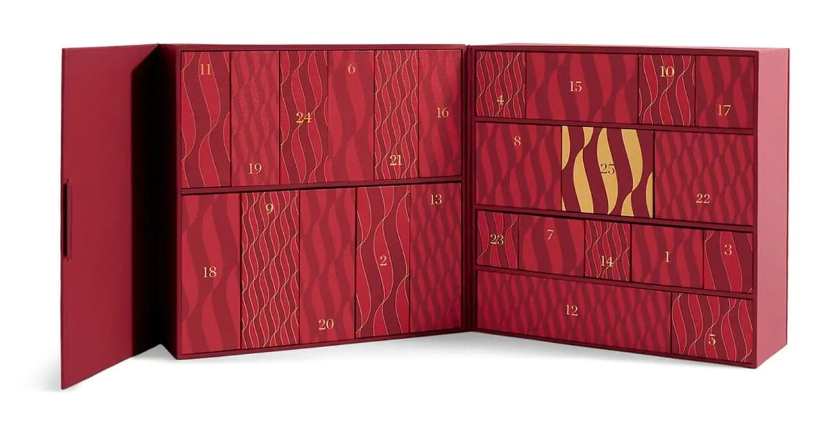 Open red keepsake advent calendar showing 25 numbered wave-patterned drawers and a gold door marked 25