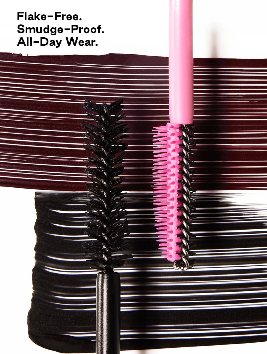 Close-up of black fibre brush and pink elastomer brush over swatches, captioned flake-free, smudge-proof, all-day wear