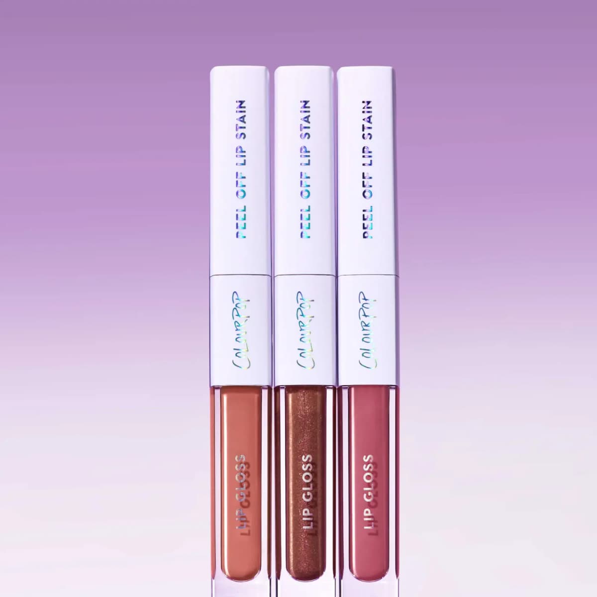 Three dual-ended lip duos with peachy nude, shimmering bronze and dusty rose glosses against a purple backdrop