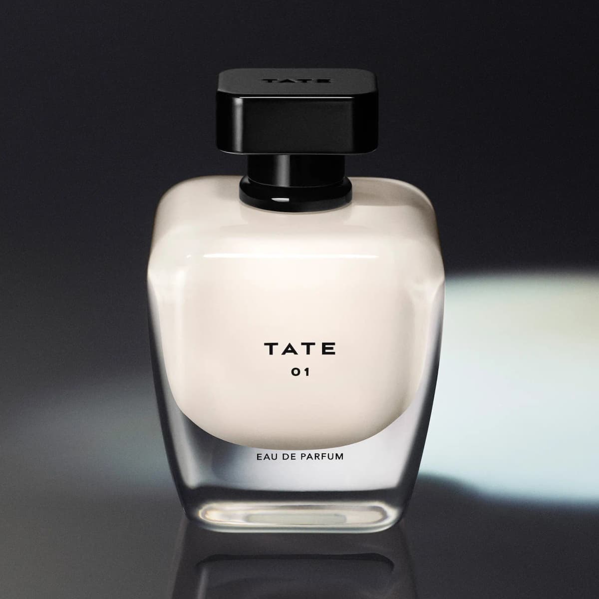 TATE 01 Eau de Parfum bottle with cream-filled glass and square black cap on a dark, reflective surface