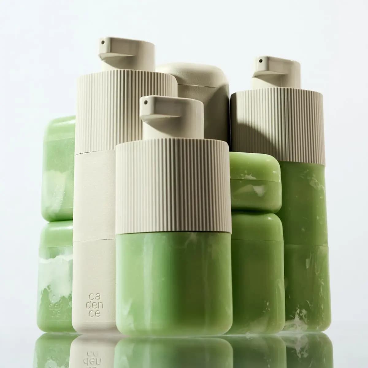 Group of cream and marbled green Pump Capsules and capsules with 'cadence' embossing, reflected below