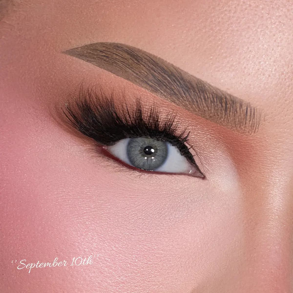 Close-up of a blue eye with fluffy elongated cat-eye lashes and winged liner, labeled 'September 10th'.