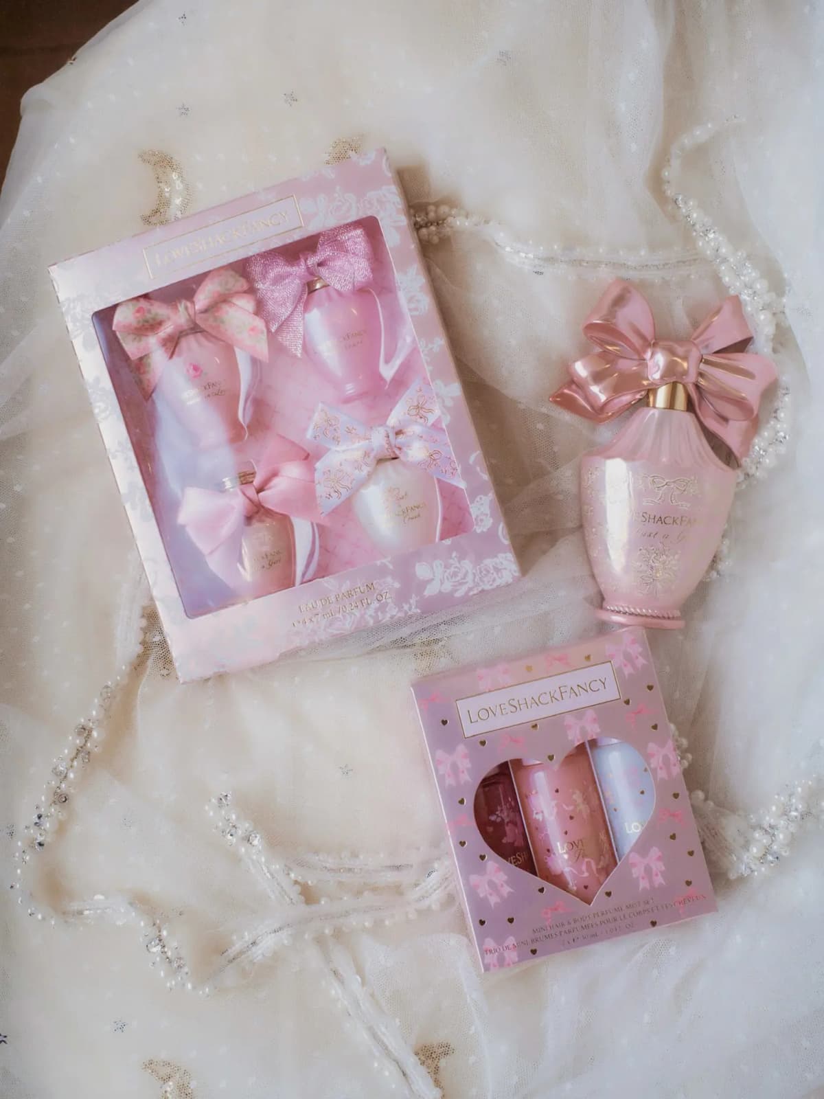 Mini Deluxe Layering Perfume Set box, pink Just a Girl bottle with sculpted bow, and heart-window mist set on white tulle