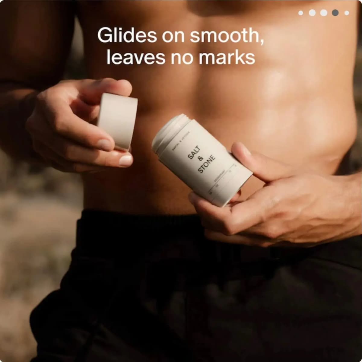 Shirtless man outdoors uncapping a cream Salt & Stone Santal & Vetiver deodorant stick under 'Glides on smooth' text.