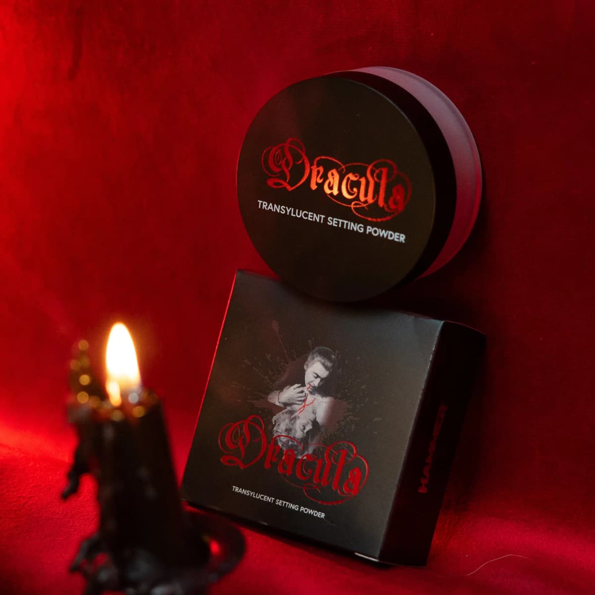 Dracula Transylucent Setting Powder jar on its box, which shows a vampire biting a woman, by candlelight