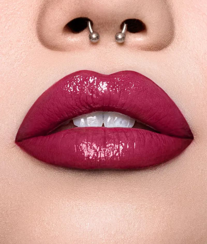 Glossy berry-red lips with a septum ring, shown in close-up on fair skin
