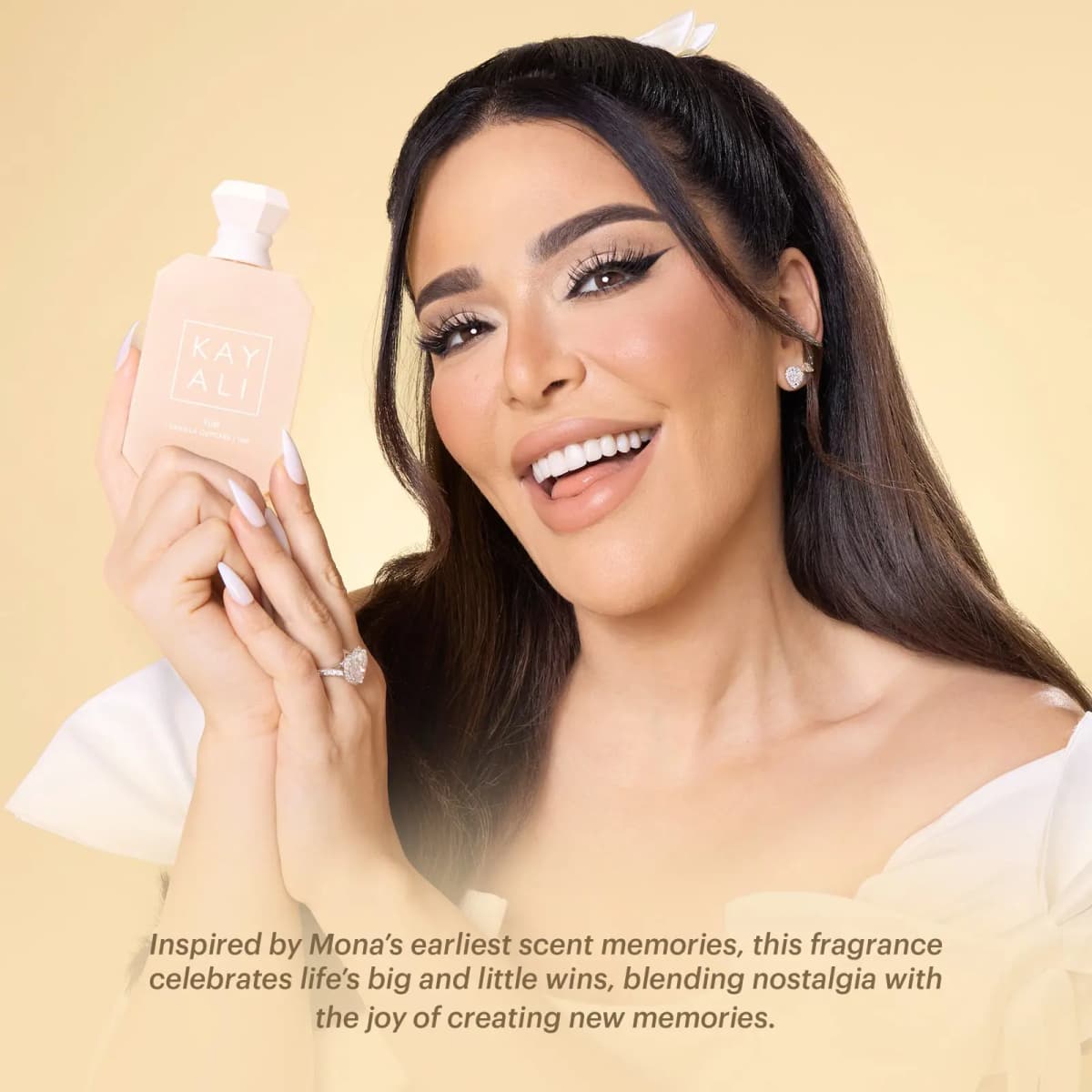 KAYALI founder Mona Kattan smiles holding the bottle against one cheek, with a caption about Mona's earliest scent memories inspiring the fragrance