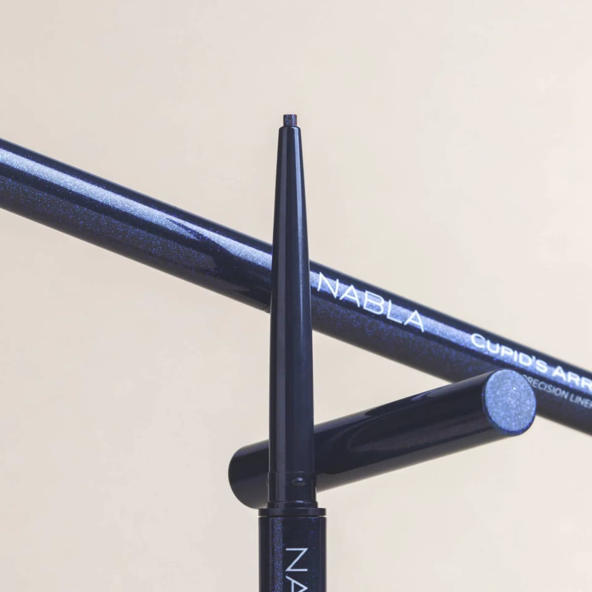 Two Blue Amber pencils and a cap crossed on a cream backdrop, glittering navy barrels with NABLA lettering.
