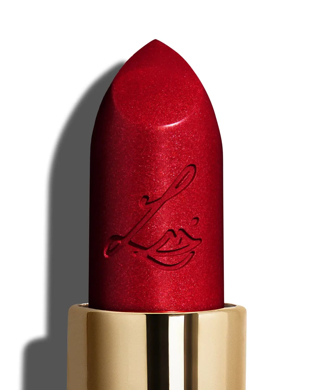 Macro shot of a shimmering red lipstick bullet engraved with the LE lips logo in a gold case