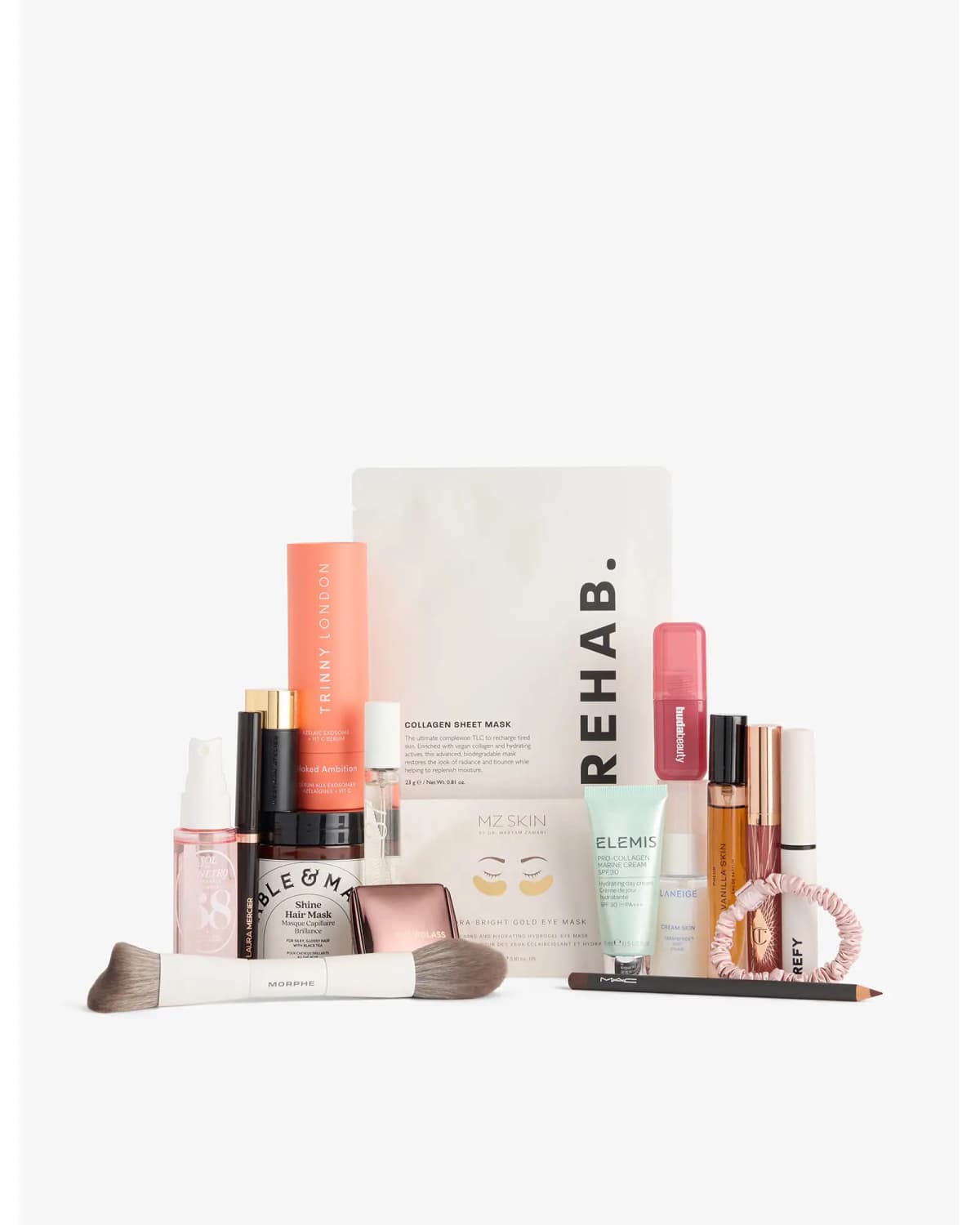 Selfridges Dream Bundle contents lined up out of the box, led by a Rehab collagen sheet mask and Trinny London serum tube
