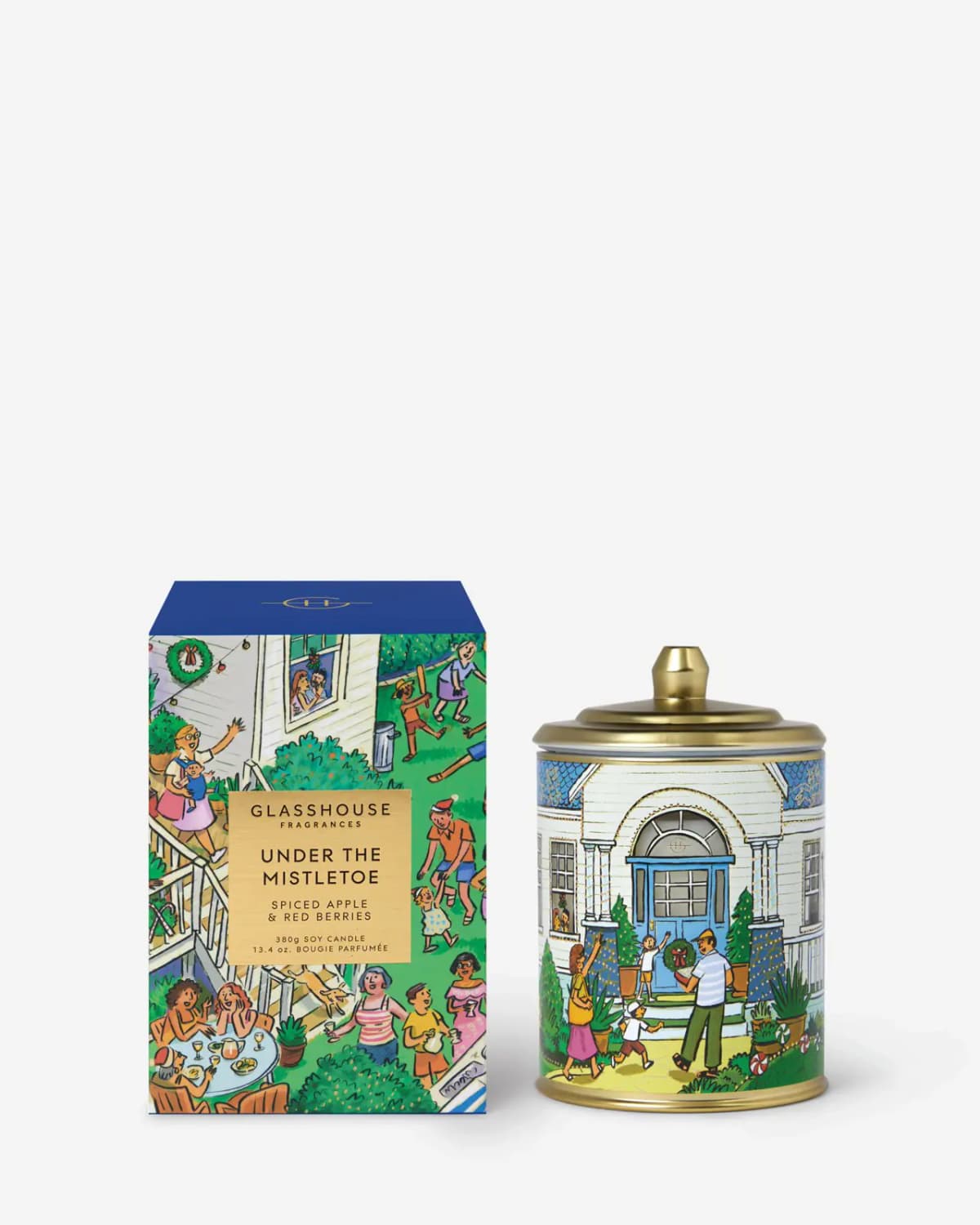 Under the Mistletoe candle with gold lid and white house scene beside its navy-topped garden-party box on white