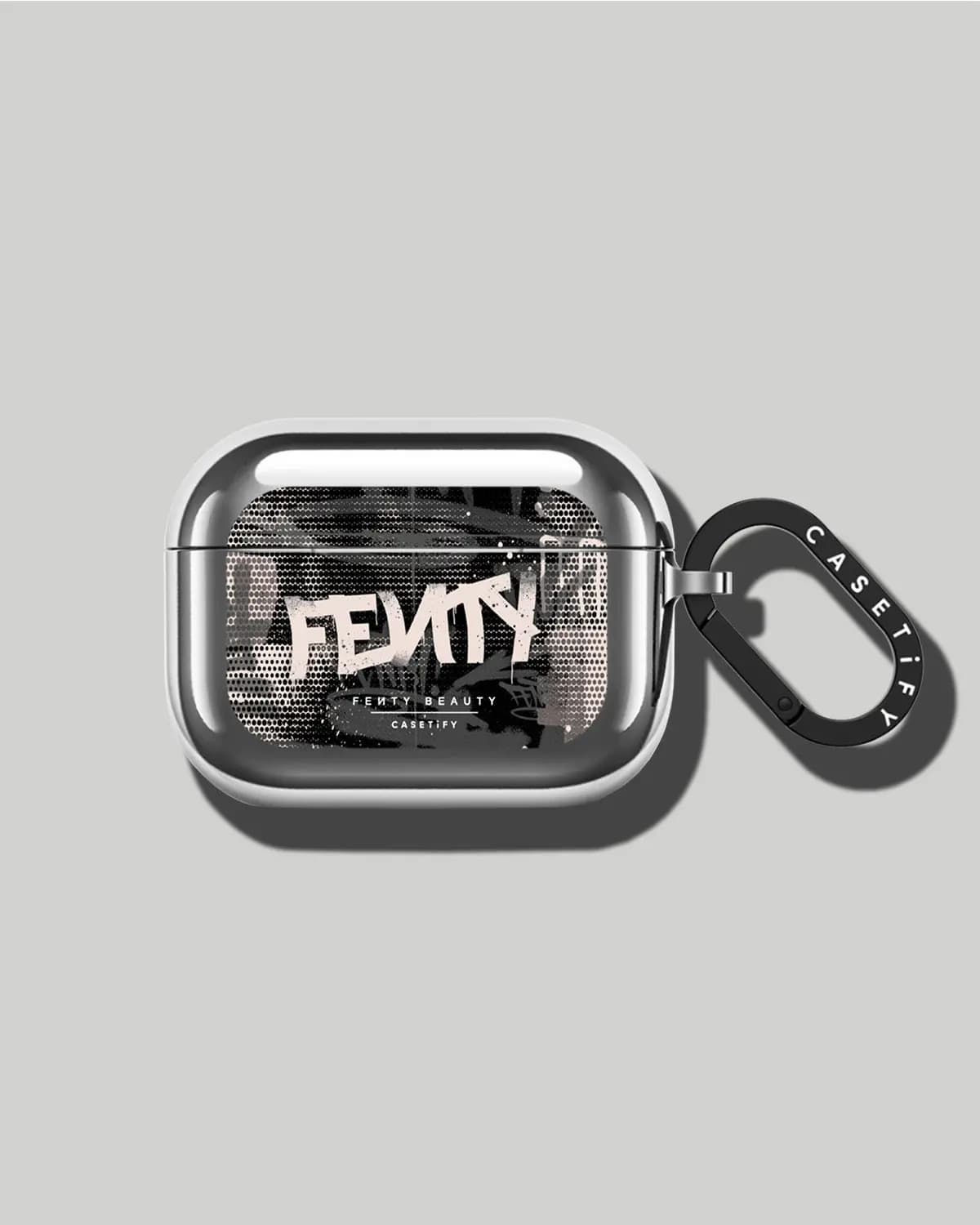 Glossy silver earbuds case printed with graffiti "Fenty" artwork, with a black CASETiFY carabiner