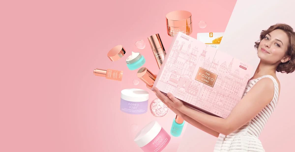 Smiling woman holding pink Stockholm-illustrated BEAR 2 Edition box as KIWI, LUNA and SUPERCHARGED products float on pink