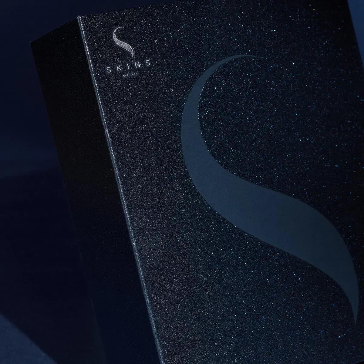 Close-up of the glittery navy Skins box with silver S logo and a large tonal S swoosh