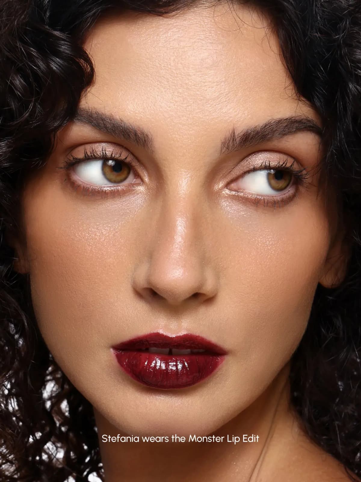 Curly-haired model Stefania wearing a glossy deep burgundy lip from the ISSY Monster Lip Edit