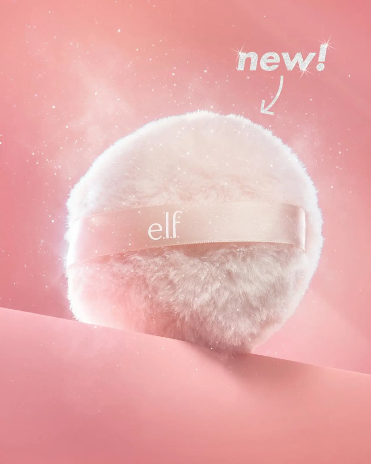 E.l.f. Halo Glow Glimmer Cloud body shimmer powder puff with pink satin strap, glitter sparkling on a pink backdrop, 'new!