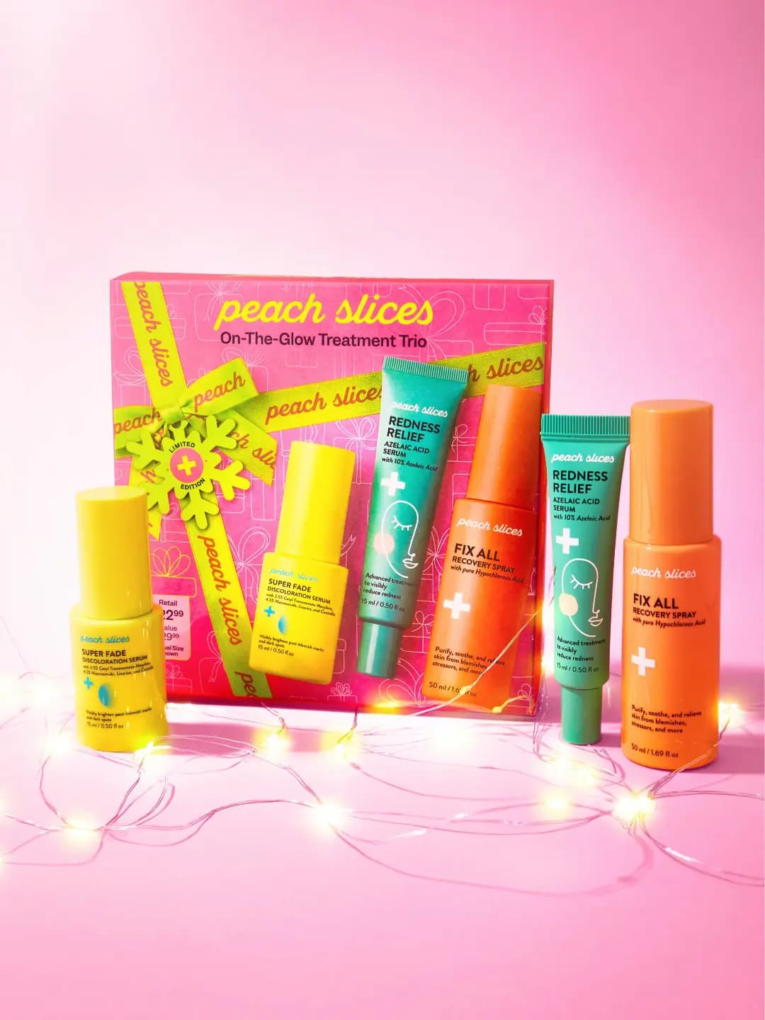 Pink Peach Slices trio box with yellow, teal and orange bottles beside it on pink, wrapped in glowing fairy lights