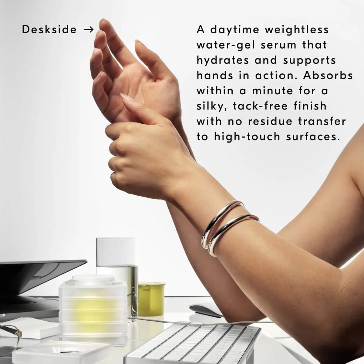 Hands massaging wrists above a desk with keyboard, water glass and the frosted dispenser, beside product description text