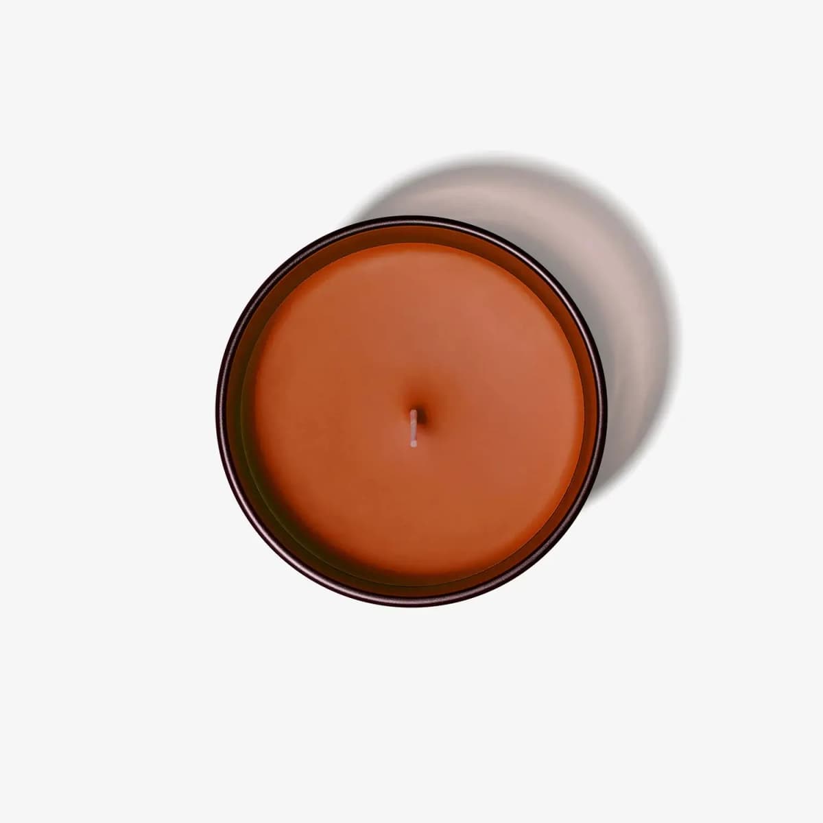Top-down view of the candle showing smooth orange wax surface and centred cotton wick in a dark-rimmed glass