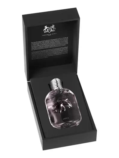Bottle nestled inside an open black presentation box with a Parfums de Marly crest and printed text on the lid