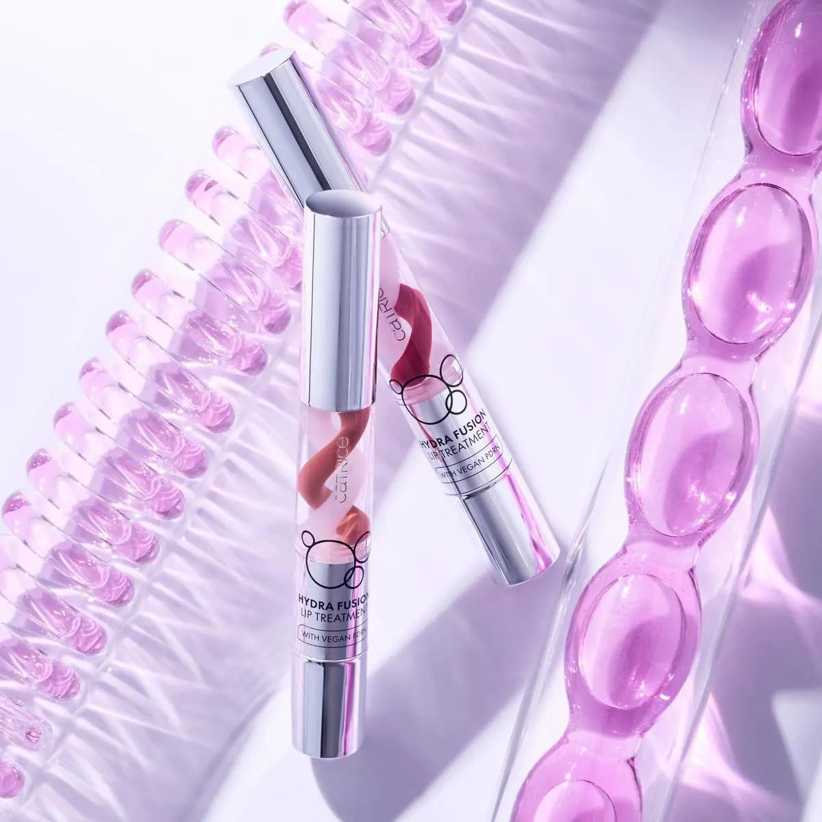 Two Hydra Fusion Lip Treatment pens with red and pink swirl formula among lilac capsules